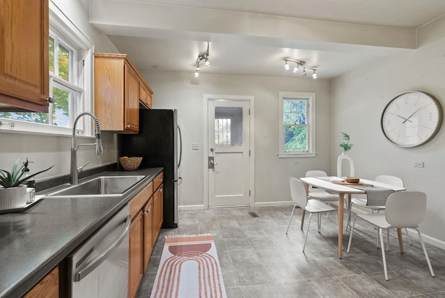 kitchen featuring dark countertops, plenty of natural light, brown cabinetry, and dishwasher