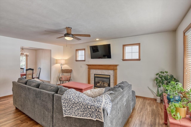 living area with a tile fireplace, plenty of natural light, and wood finished floors