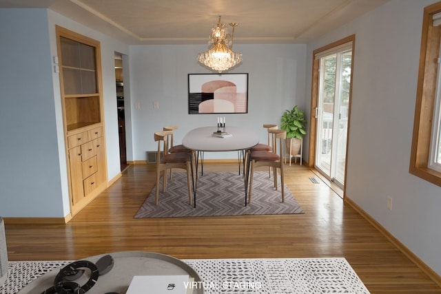 dining area featuring visible vents, baseboards, wood finished floors, an inviting chandelier, and built in shelves