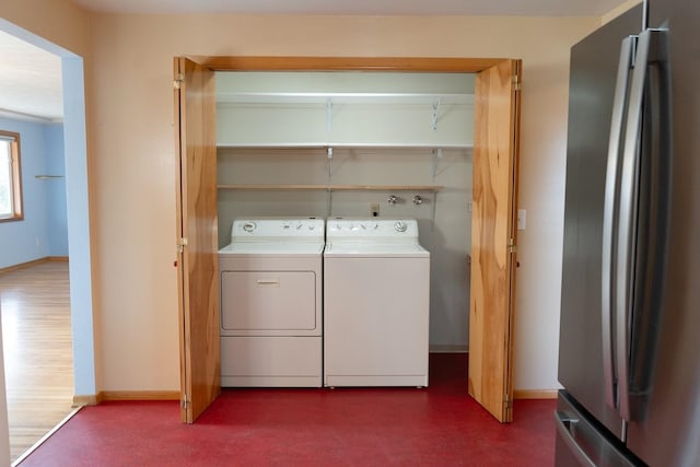 laundry room featuring laundry area, dark floors, baseboards, and washing machine and clothes dryer