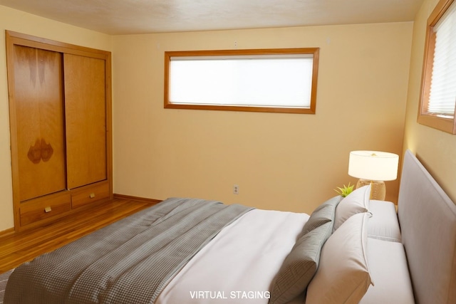 bedroom with a closet, baseboards, and wood finished floors