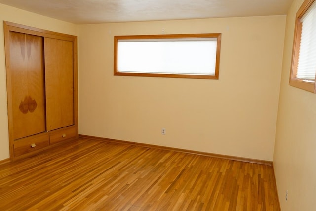 unfurnished bedroom with baseboards, a closet, and light wood-style floors