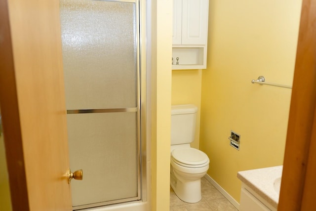 bathroom featuring a shower with door, toilet, vanity, tile patterned flooring, and baseboards