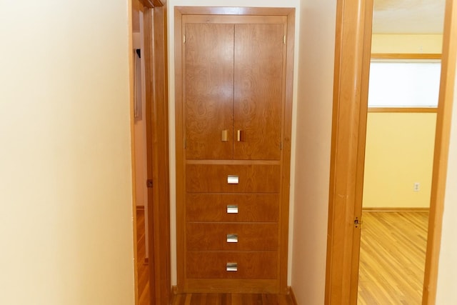 corridor with baseboards and wood finished floors