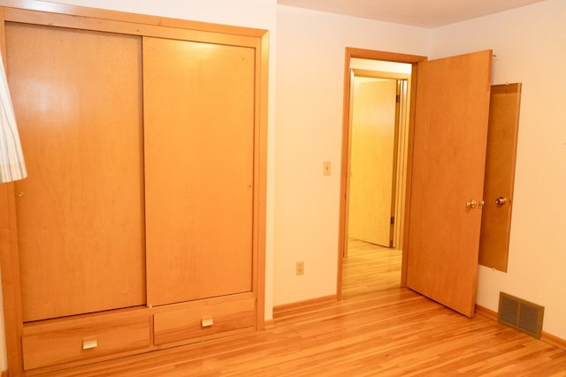 unfurnished bedroom featuring light wood-style floors, a closet, visible vents, and baseboards