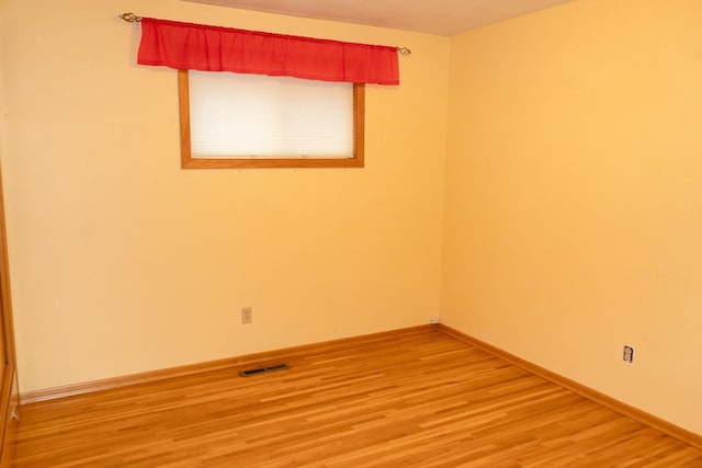 unfurnished room featuring light wood-style flooring, visible vents, and baseboards