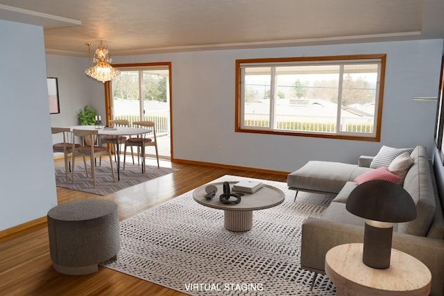 living area featuring a notable chandelier, baseboards, and wood finished floors