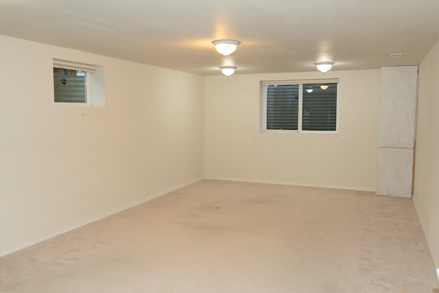 spare room with baseboards and light colored carpet