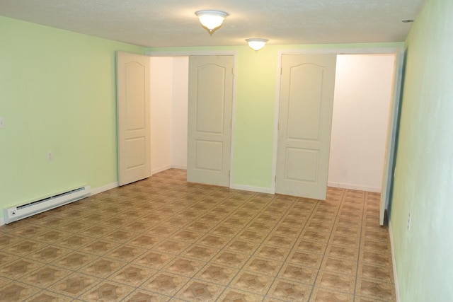 unfurnished bedroom with a baseboard heating unit and baseboards