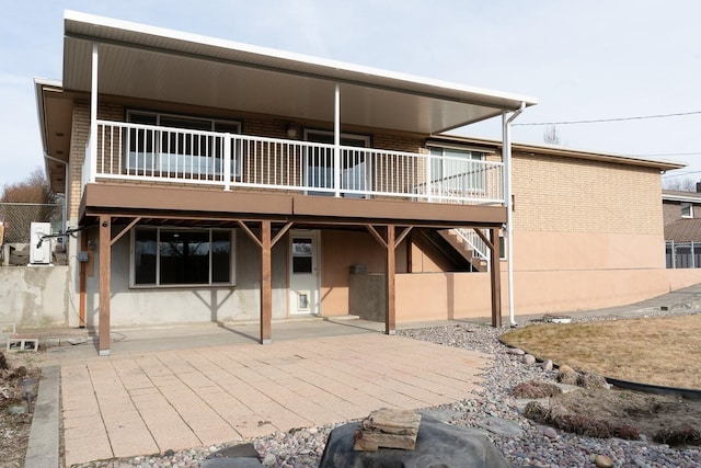 rear view of property with a patio area, brick siding, and stairway