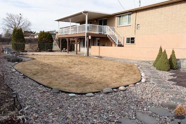 back of house with brick siding, fence, stairs, a wooden deck, and a patio area