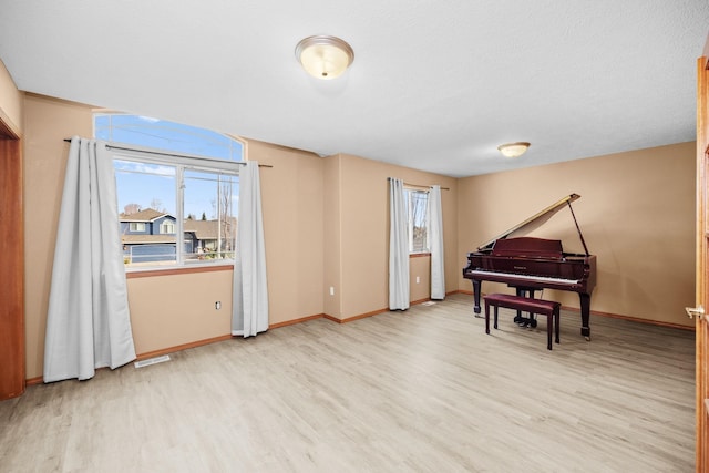 living area with a healthy amount of sunlight, visible vents, baseboards, and wood finished floors