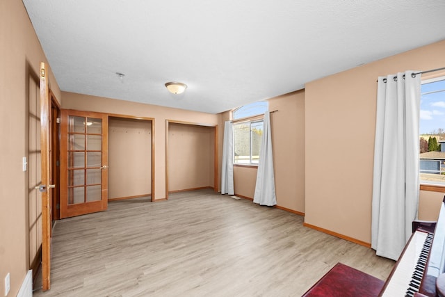 interior space with light wood-style flooring, baseboards, and a textured ceiling