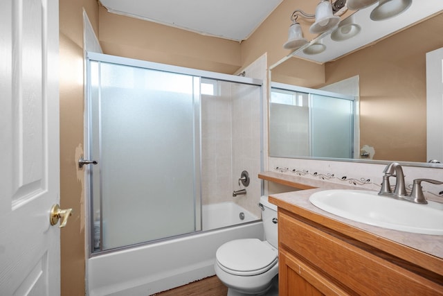 bathroom featuring toilet, combined bath / shower with glass door, and vanity