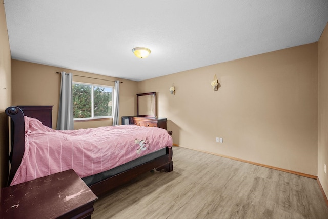 bedroom with baseboards and wood finished floors