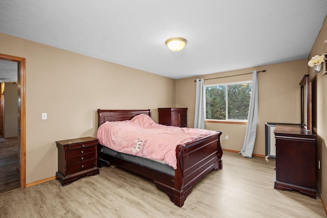 bedroom with light wood finished floors and baseboards