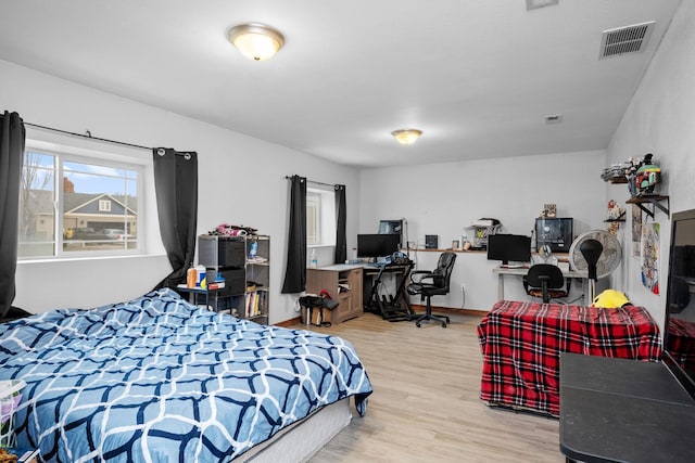 bedroom with visible vents, baseboards, and wood finished floors