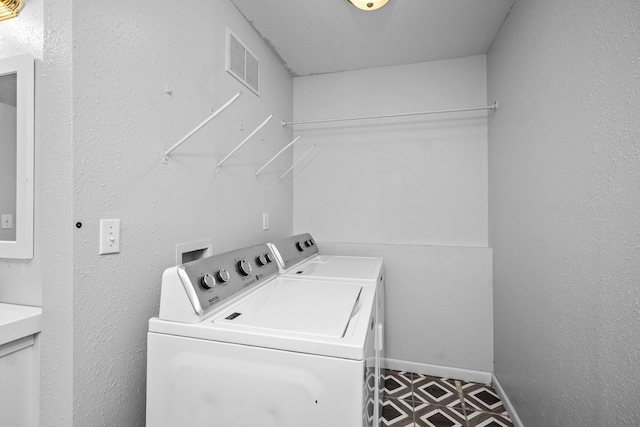 washroom with washing machine and dryer, laundry area, visible vents, baseboards, and tile patterned floors