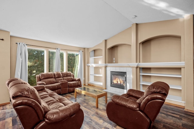 living room featuring built in features, vaulted ceiling, a tiled fireplace, and wood finished floors