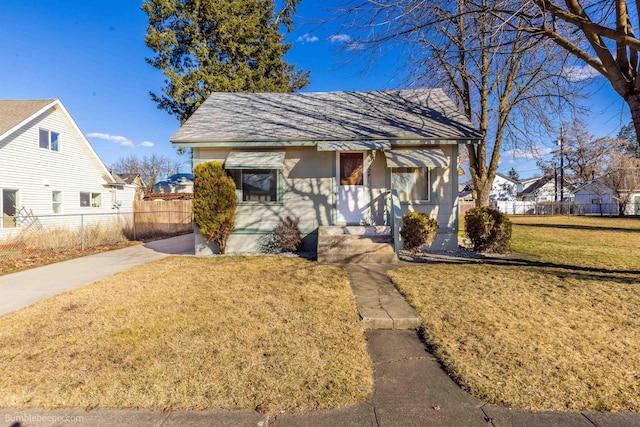 bungalow-style home featuring a shingled roof, a front yard, and fence