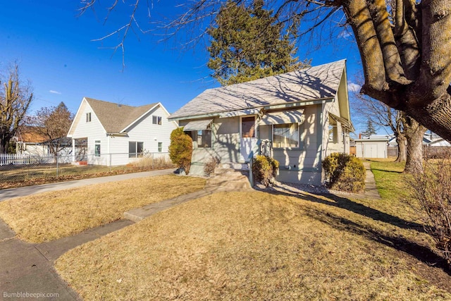 bungalow-style home with a front yard and fence