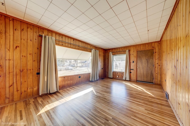 interior space with light wood-style floors, visible vents, and wood walls