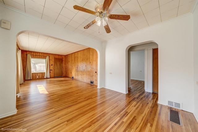 unfurnished room with arched walkways, visible vents, and light wood-style flooring