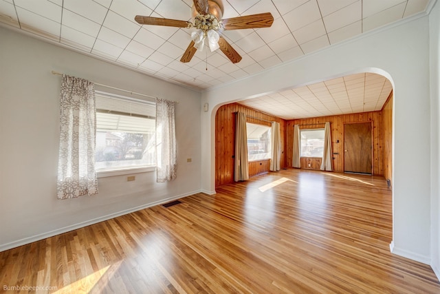 empty room with plenty of natural light, visible vents, arched walkways, and light wood-style flooring