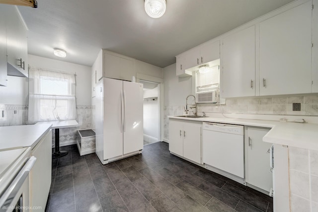 kitchen featuring white appliances, white cabinetry, light countertops, and a sink