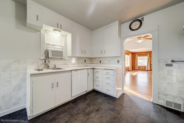 kitchen featuring white dishwasher, a sink, visible vents, and tile walls