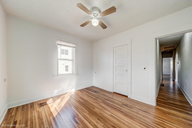 unfurnished bedroom with a textured ceiling, wood finished floors, visible vents, and baseboards