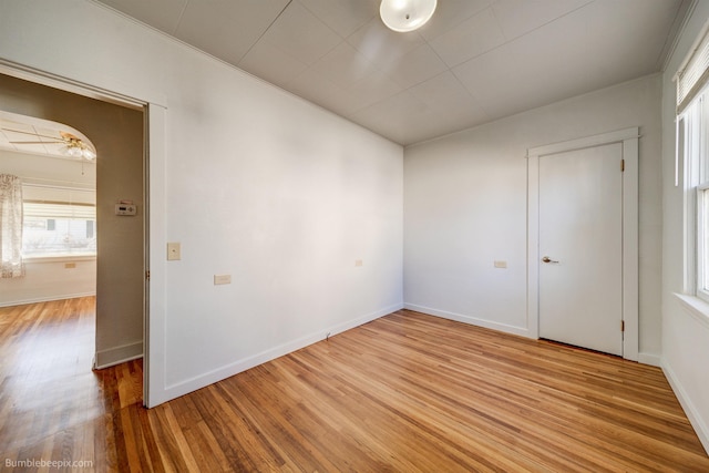 unfurnished room featuring baseboards, a ceiling fan, and light wood-style floors