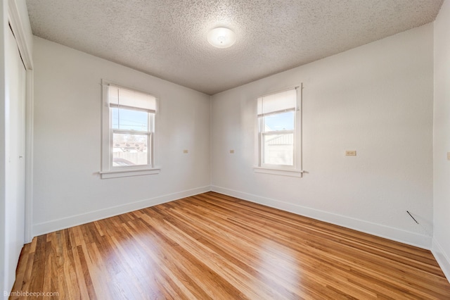 spare room with light wood-type flooring, a wealth of natural light, and baseboards