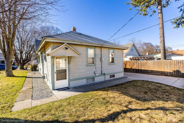 bungalow with a front yard, fence, a chimney, and a patio