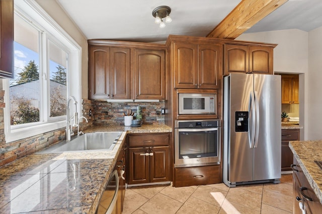 kitchen featuring light tile patterned floors, backsplash, appliances with stainless steel finishes, a sink, and beamed ceiling