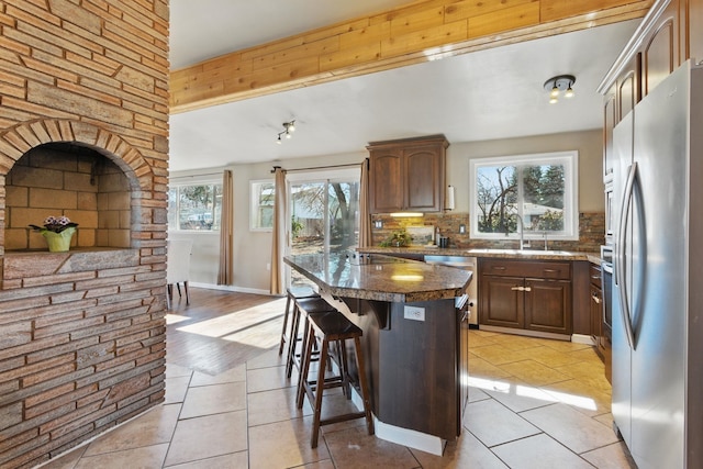 kitchen featuring a breakfast bar, decorative backsplash, appliances with stainless steel finishes, a sink, and a kitchen island