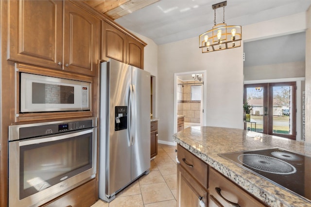 kitchen featuring brown cabinets, a notable chandelier, light tile patterned floors, stainless steel appliances, and hanging light fixtures