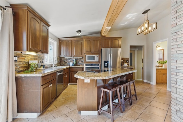 kitchen with lofted ceiling with beams, appliances with stainless steel finishes, a breakfast bar, backsplash, and a sink