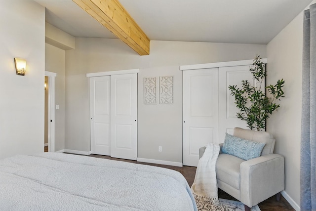 bedroom with lofted ceiling with beams, baseboards, and two closets