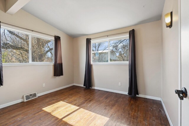 unfurnished room featuring lofted ceiling, wood-type flooring, visible vents, and baseboards