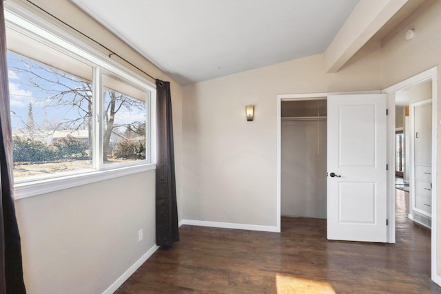 unfurnished bedroom with vaulted ceiling with beams, a closet, baseboards, and wood finished floors