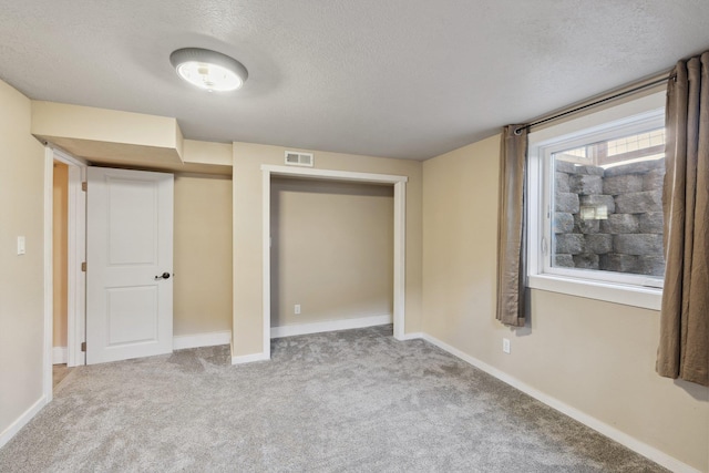 unfurnished bedroom with carpet, a textured ceiling, and baseboards