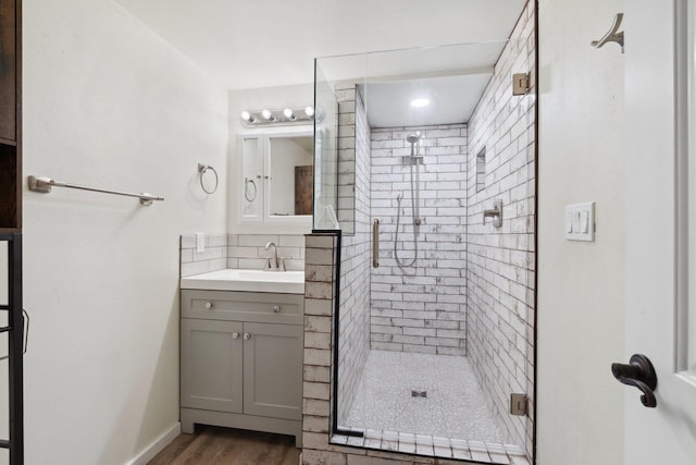 bathroom featuring a stall shower, decorative backsplash, wood finished floors, and vanity