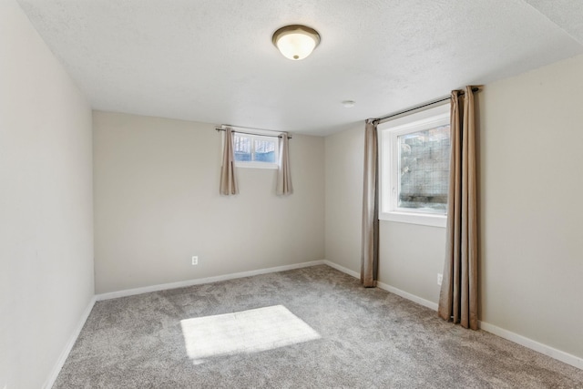 carpeted spare room featuring baseboards and a textured ceiling