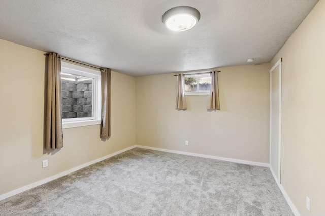 empty room featuring carpet, a textured ceiling, and baseboards