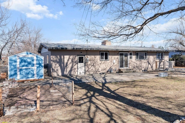 back of house with entry steps, an outbuilding, fence, a shed, and a chimney