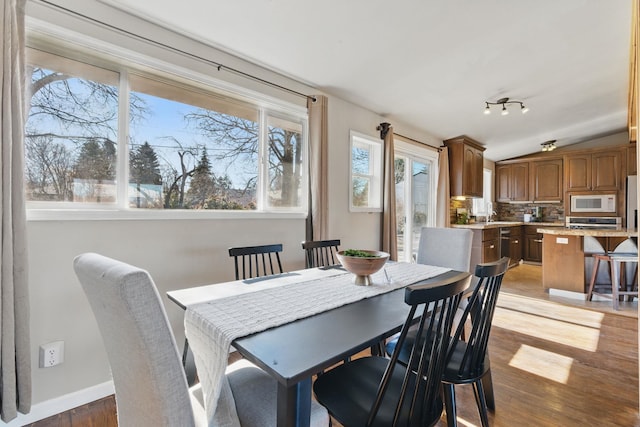 dining area featuring lofted ceiling, light wood finished floors, and baseboards