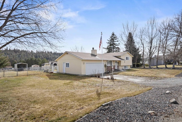 exterior space with a chimney, concrete driveway, a lawn, an attached garage, and fence