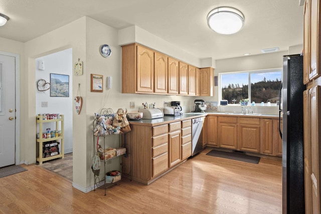 kitchen featuring light wood-type flooring, white dishwasher, a sink, and freestanding refrigerator