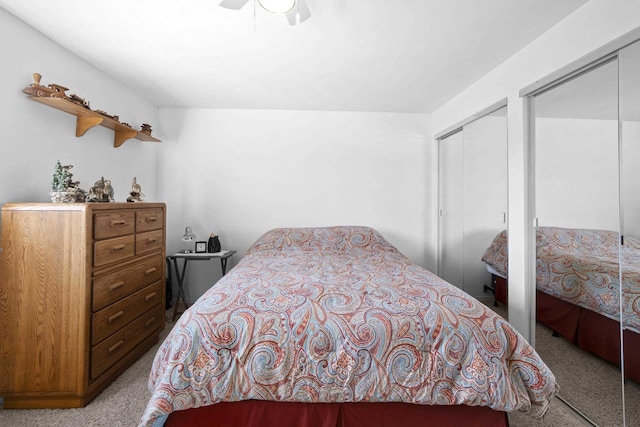 bedroom featuring carpet, a ceiling fan, and multiple closets